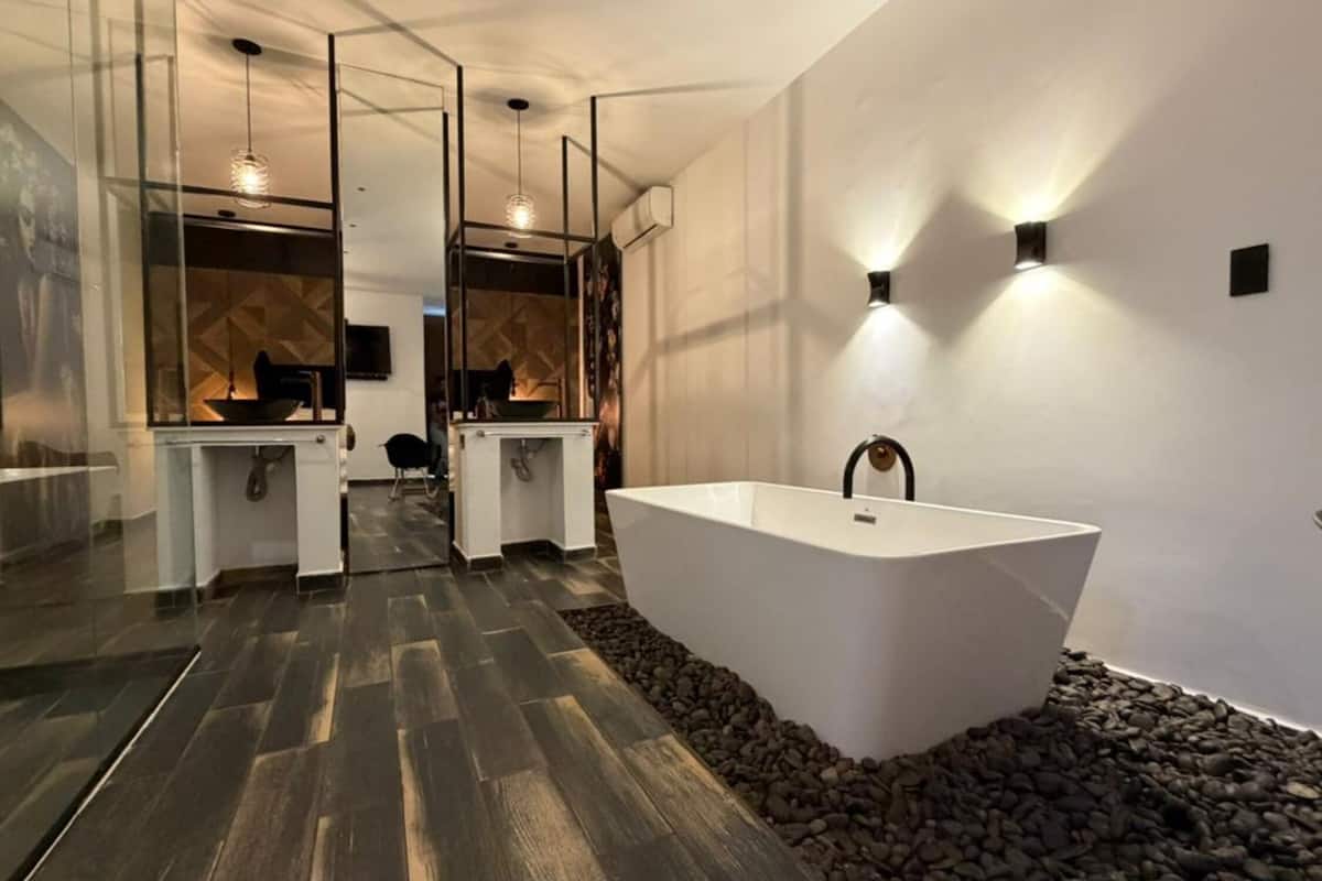 A modern bathroom with a freestanding bathtub, a glass partition, and a stone accent wall.