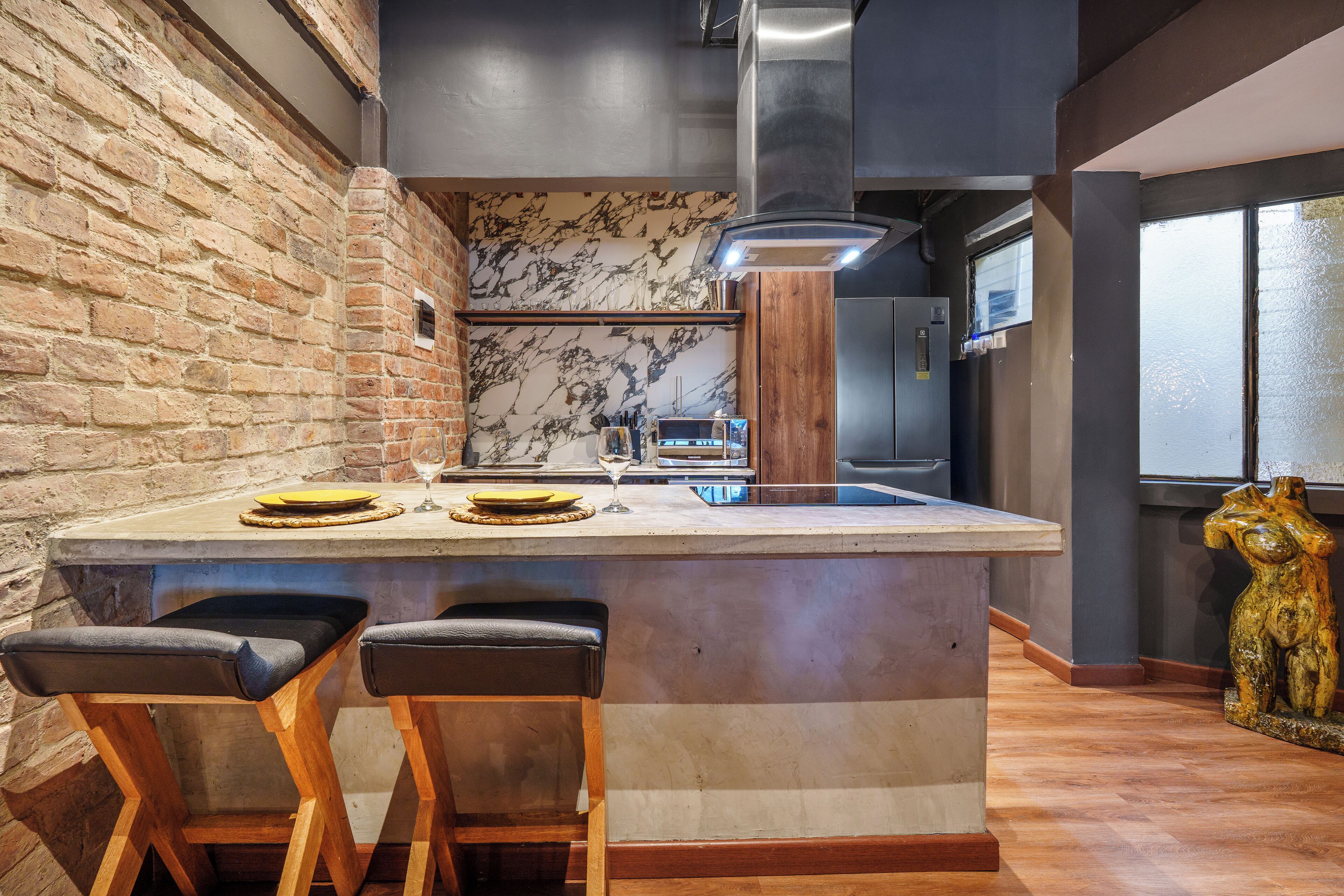 A kitchen with a marble backsplash, a central island with stools, and a decorative wooden sculpture.