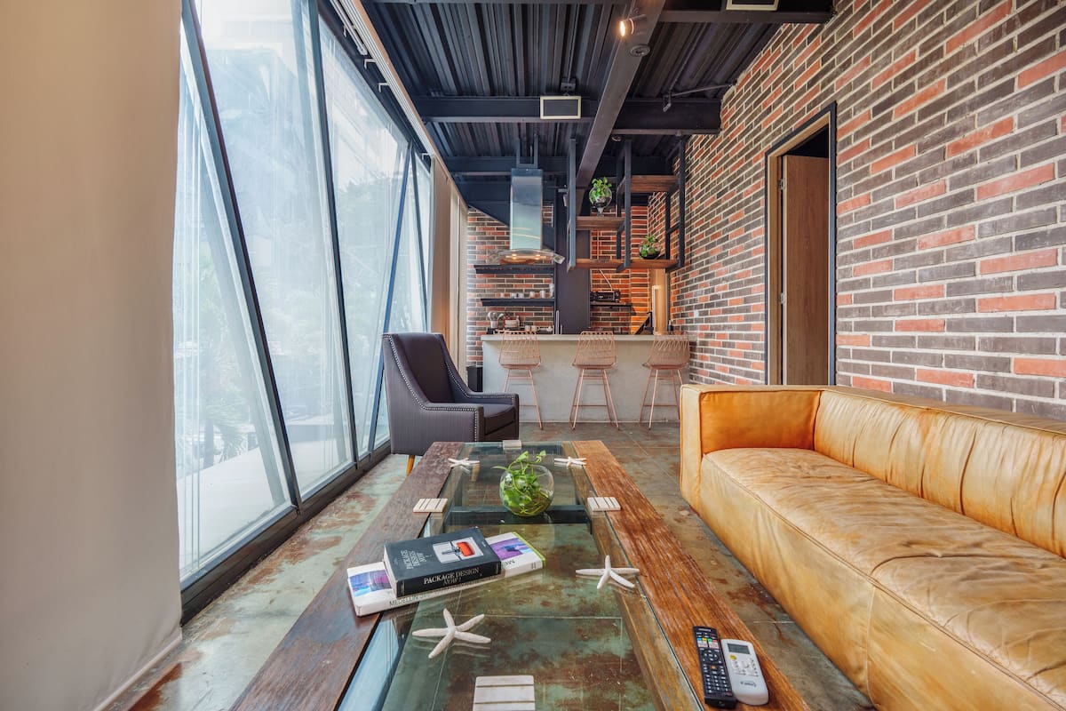 A modern interior with a leather sofa, a glass coffee table with decorative items, and a brick wall.