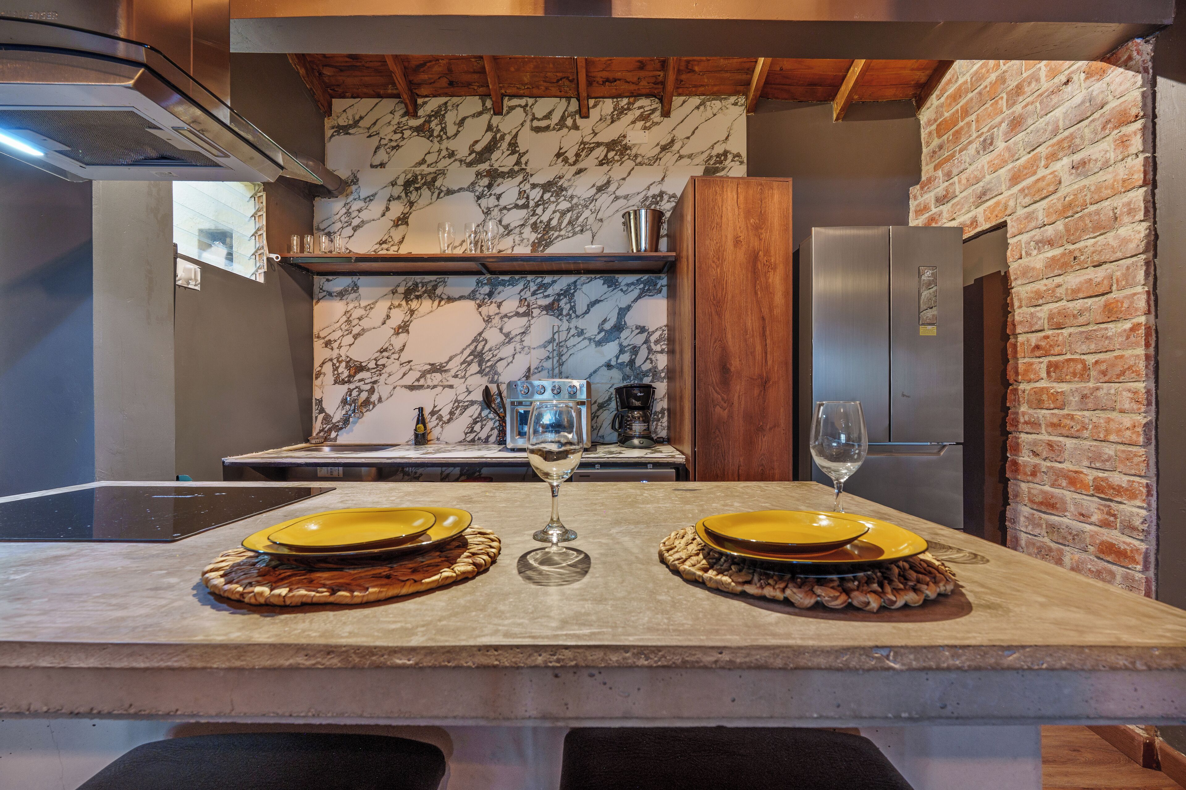 A kitchen with marble backsplash, wooden beams, and a brick wall.