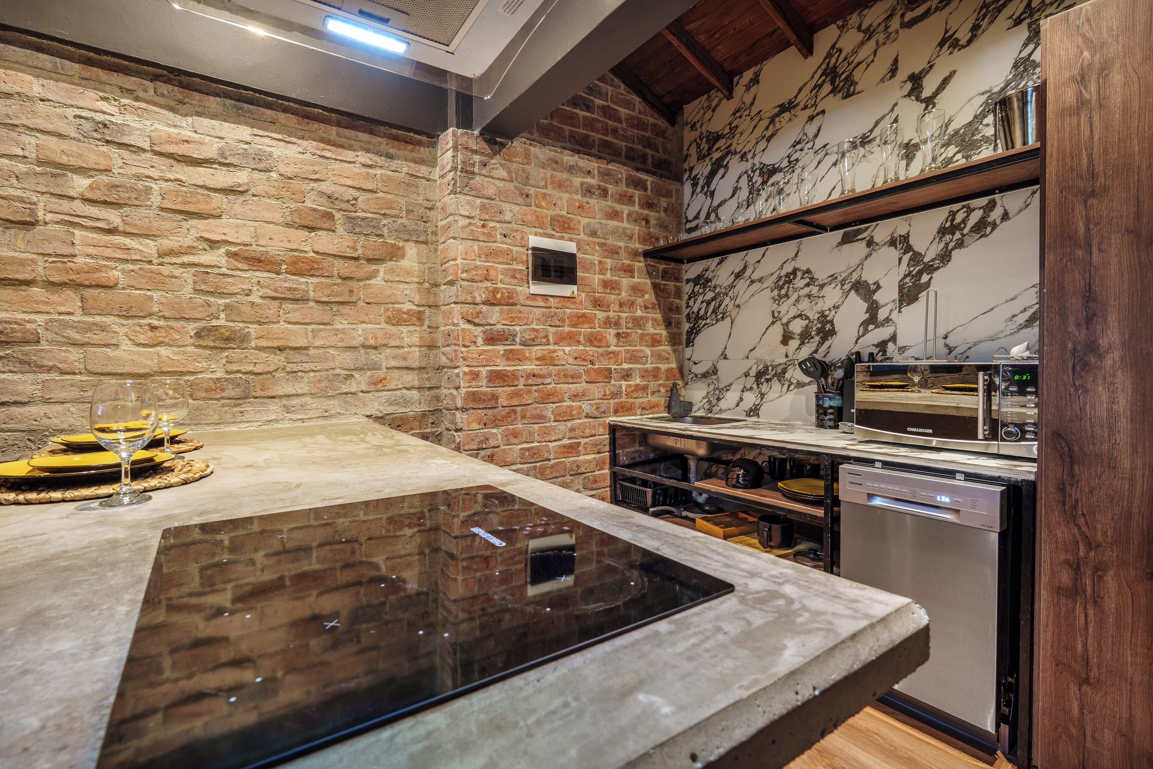A kitchen with a brick wall, a marble backsplash, and a built-in oven.