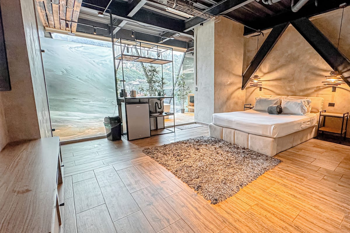 A modern bedroom with a bed, bedside tables, a rug, and a view of the outdoors.