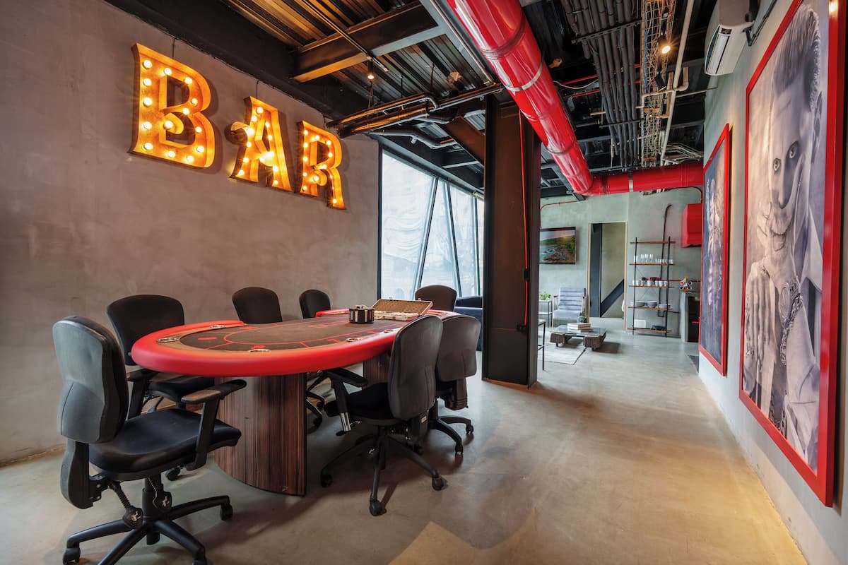 A conference room with a large table, chairs, and a neon sign that reads "BAR".