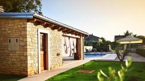 Ein Steinhaus mit Pool und überdachter Terrasse.