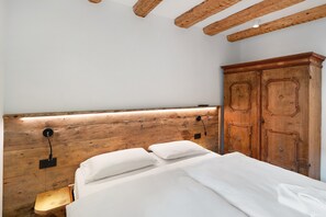 Una camera da letto con una testiera in legno, un letto con lenzuola bianche, un comodino con una lampada e un'armadio in legno.