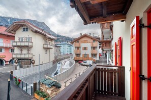 Una vista di una strada con edifici, una recinzione in legno e una porta rossa.