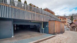 Ein Gebäude mit einer Garage, einer Rampe und einem Holzzaun mit Bepflanzung.