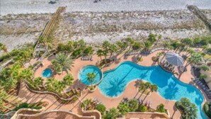 Een resort met een groot zwembad, palmbomen en een strand.