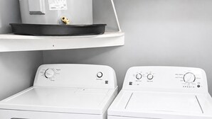 Zwei Frontlader-Waschmaschinen mit Bedienfeldern, ein weißes Regal darüber und eine weiße Wand.