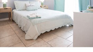 Ein Schlafzimmer mit einem Bett, zwei Nachttischen, einer Kommode und einem Fenster mit Vorhängen.