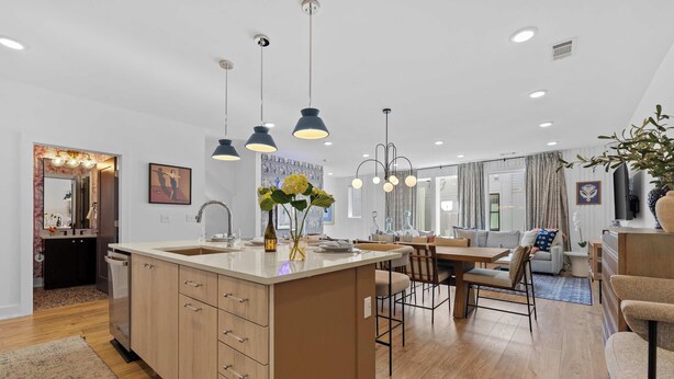Une cuisine moderne dotée d’un îlot central, de luminaires suspendus et d’un coin repas avec un canapé et des chaises.
