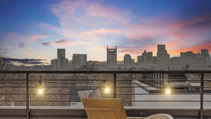 Une terrasse sur le toit offrant une vue sur les toits de la ville, une chaise en bois et une table.
