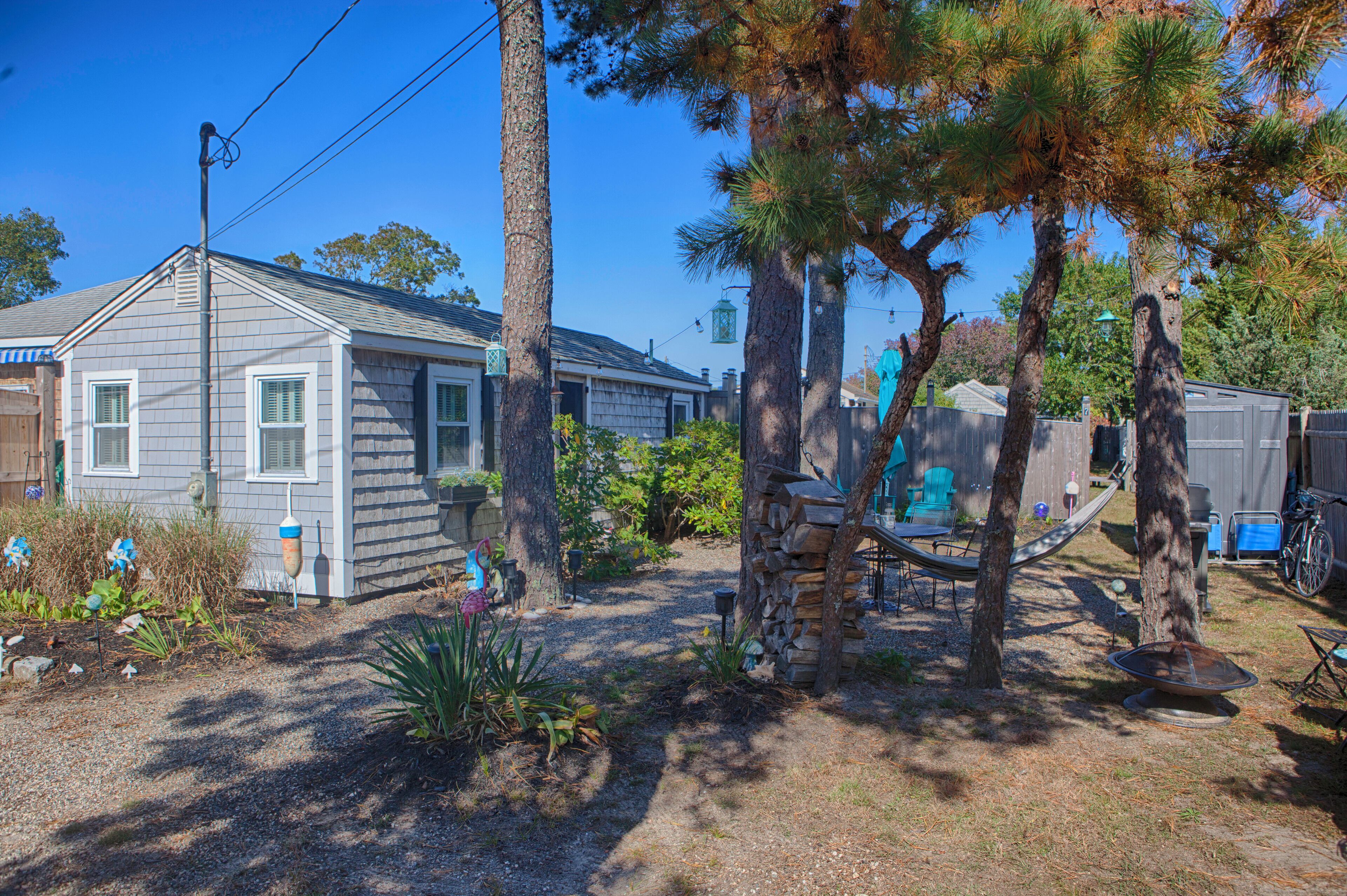 A residential property with a detached house, a hammock, and a backyard with trees and plants.