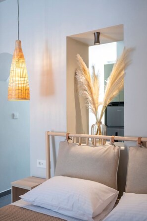 A bedroom with a bed, bedside tables, a hanging light fixture, a mirror, and a vase with pampas grass. - Aram`s Luxury Port House (Kos)