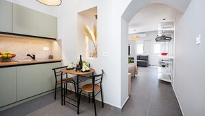Eine moderne Küche mit Essbereich, einer sichtbaren Küchenarbeitsfläche mit Früchten und einem Esstisch mit Stühlen.