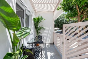 A balcony with a table and chairs, potted plants, and a white railing. - Aram`s Luxury Port House (Kos)