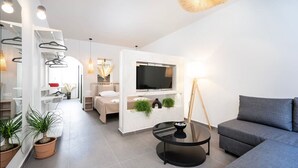 Ein modernes Wohnzimmer mit einem grauen Sofa, einem schwarzen Couchtisch und einem an der Wand befestigten Fernseher. Üchtige Pflanzen und eine Pendelleuchte sind ebenfalls vorhanden.