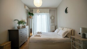 Une chambre à coucher comprenant un lit, une commode, une table de chevet, une lampe et une plante en pot.