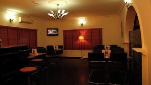 A dimly lit room with a chandelier, a television mounted on the wall, and a table with chairs. - Lekki Suites (Lekki)