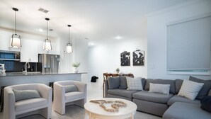 A modern living room with a grey sofa, two white armchairs, and a round coffee table. - Disney Area 4BR Home w/ Pool & Themed Rooms (Davenport)