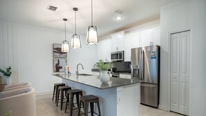 A modern kitchen with a central island, stainless steel appliances, and pendant lighting. - Disney Area 4BR Home w/ Pool & Themed Rooms (Davenport)