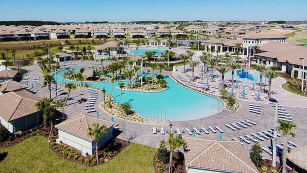 A resort with a large central pool, multiple smaller pools, and a well-maintained landscape with palm trees and lounge areas. - Disney Area 4BR Home w/ Pool & Themed Rooms (Davenport)