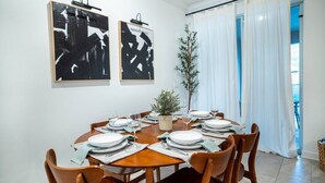 A dining area with a round wooden table set for six, white plates, and glasses. Two abstract paintings hang on the wall above the table. - Disney Area 4BR Home w/ Pool & Themed Rooms (Davenport)
