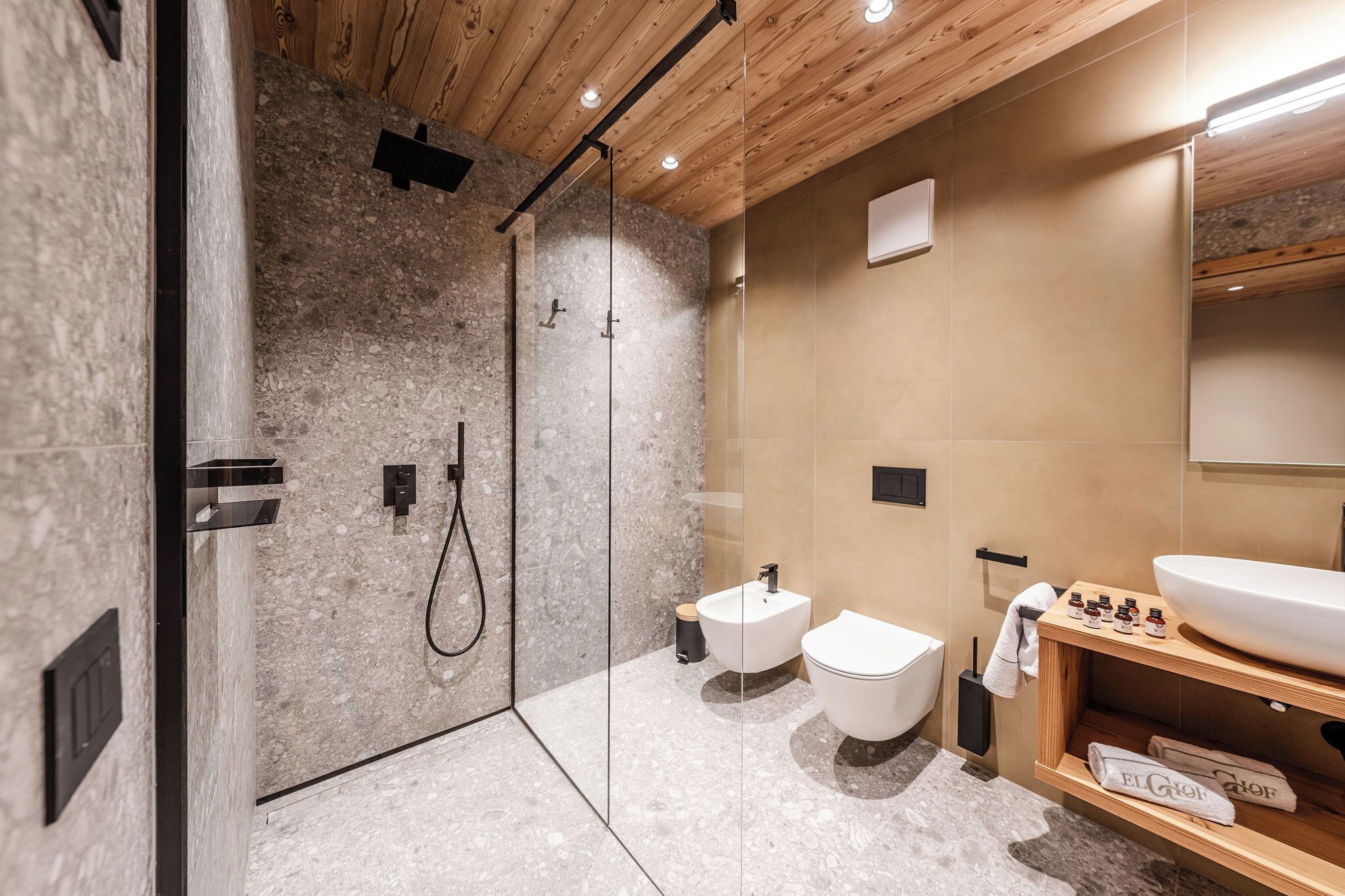 Une salle de bain moderne dotée d’une douche à parois de verre, de toilettes sur pied et d’un meuble-lavabo avec un grand évier et des étagères de rangement.