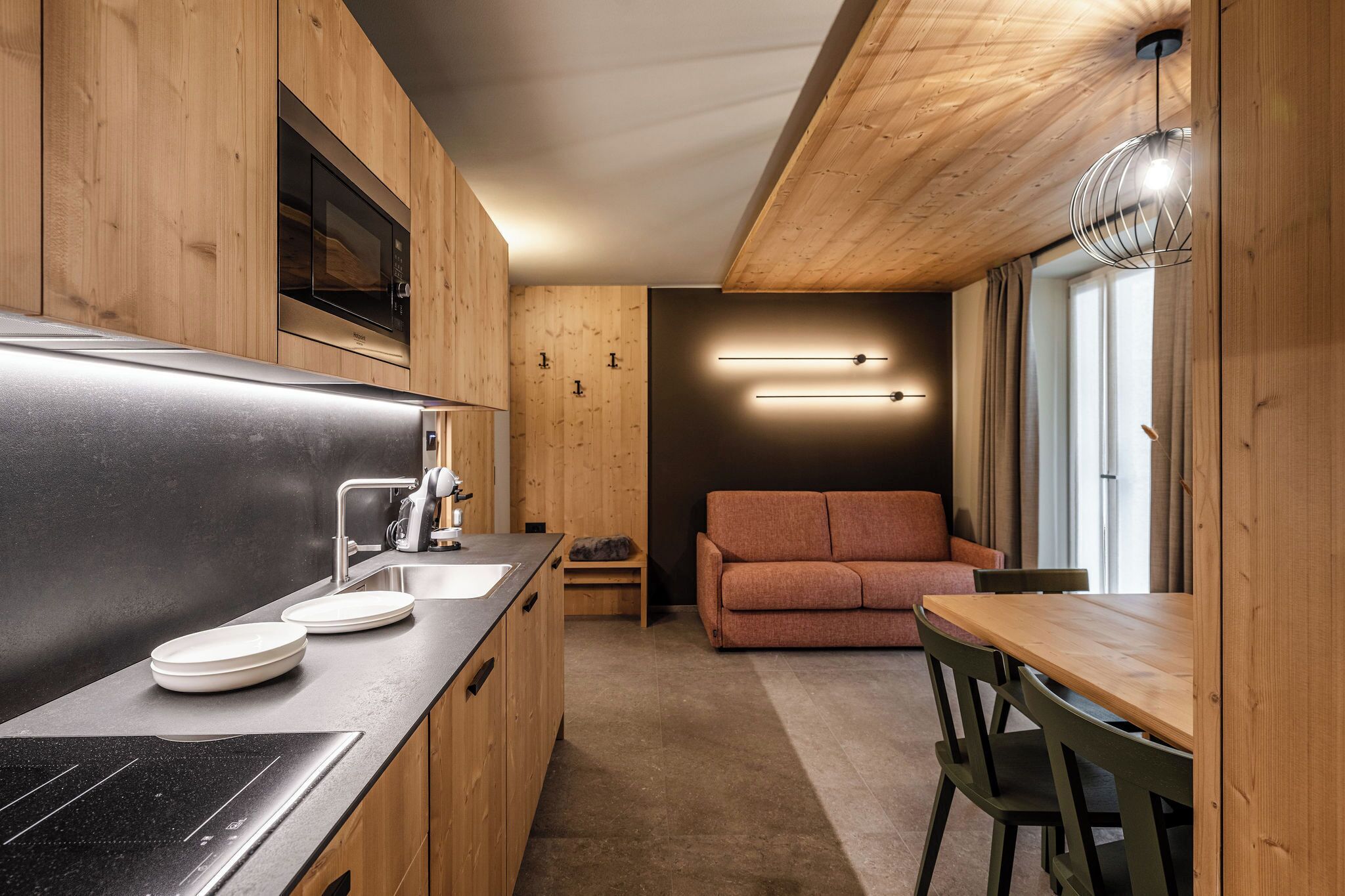 Una cocina compacta con armarios de madera, microondas integrado y estufa moderna.