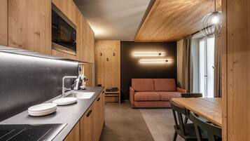 Una cocina compacta con armarios de madera, microondas integrado y estufa moderna.