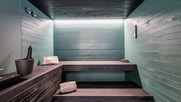 A sauna room with wooden benches, a small table, and a towel.
