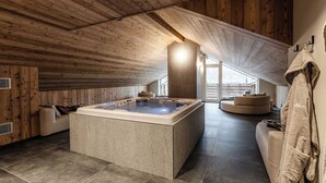 A modern spa area with a large hot tub, wooden ceiling, and a cozy seating area. - El Giof Alpine Home (Pellizzano)