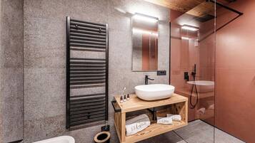 Een moderne badkamer met een vrijstaand bad, een houten wastafelmeubel met een grote wastafel, een handdoekrek en een douchecabine met glazen wanden.