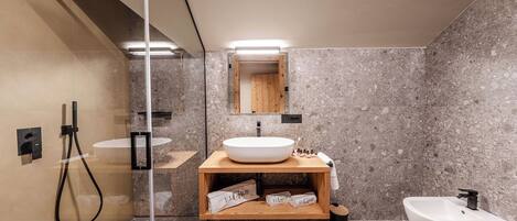 A modern bathroom with a large mirror, a wooden vanity, a freestanding sink, and a bidet.