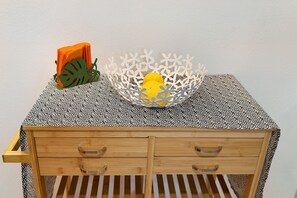 A small wooden table with a patterned tablecloth, a decorative white basket, and a yellow object inside. - Studio Apartment 'Quercia -in Caruggiu Di Via Vecchia' with Mountain View, Wi-Fi and Air Conditioning (orco feglino)
