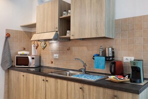 Una cocina con microondas, cafetera y lavamanos.