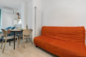 Un espace de vie comprenant un canapé, des fauteuils, une table et un radiateur.