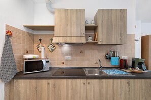 Une cuisine équipée de meubles en bois, d’un four à micro-ondes, d’une bouilloire et d’une machine à café.