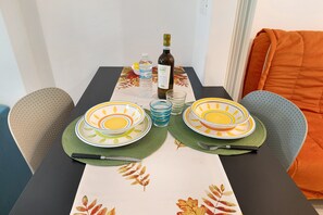 Une table à manger dressée avec des assiettes, une bouteille, des verres et une bouteille d’eau.
