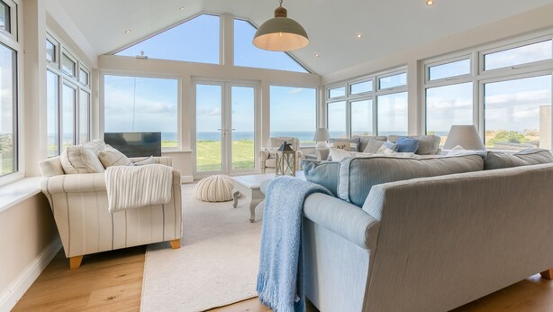 A spacious living room with large windows, a television, and comfortable seating. - Hafan Nefyn - sleeps 8 guests  in 4 bedrooms (Nefyn)