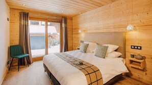 Un dormitorio con paneles de madera, una cama, una silla y una mesita de noche con una tetera.