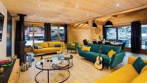 Una sala de estar moderna con techos de madera, un sofá amarillo, un sofá verde y una mesa de centro de vidrio.