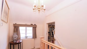 En trappa som leder upp till en liten plattform med ett element, ett bord med en vas och en bokhylla.