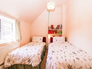 A bedroom with two single beds, a bookshelf, and a window. - Vine Cottage (Tewkesbury)