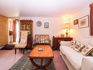 Un salon traditionnel avec une table basse en bois, un canapé, un fauteuil, une commode et une lampe.