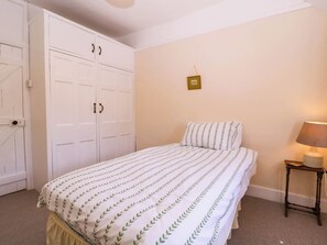 Una camera da letto con un letto, un comodino, una lampada, un armadio e un interruttore della luce a parete.