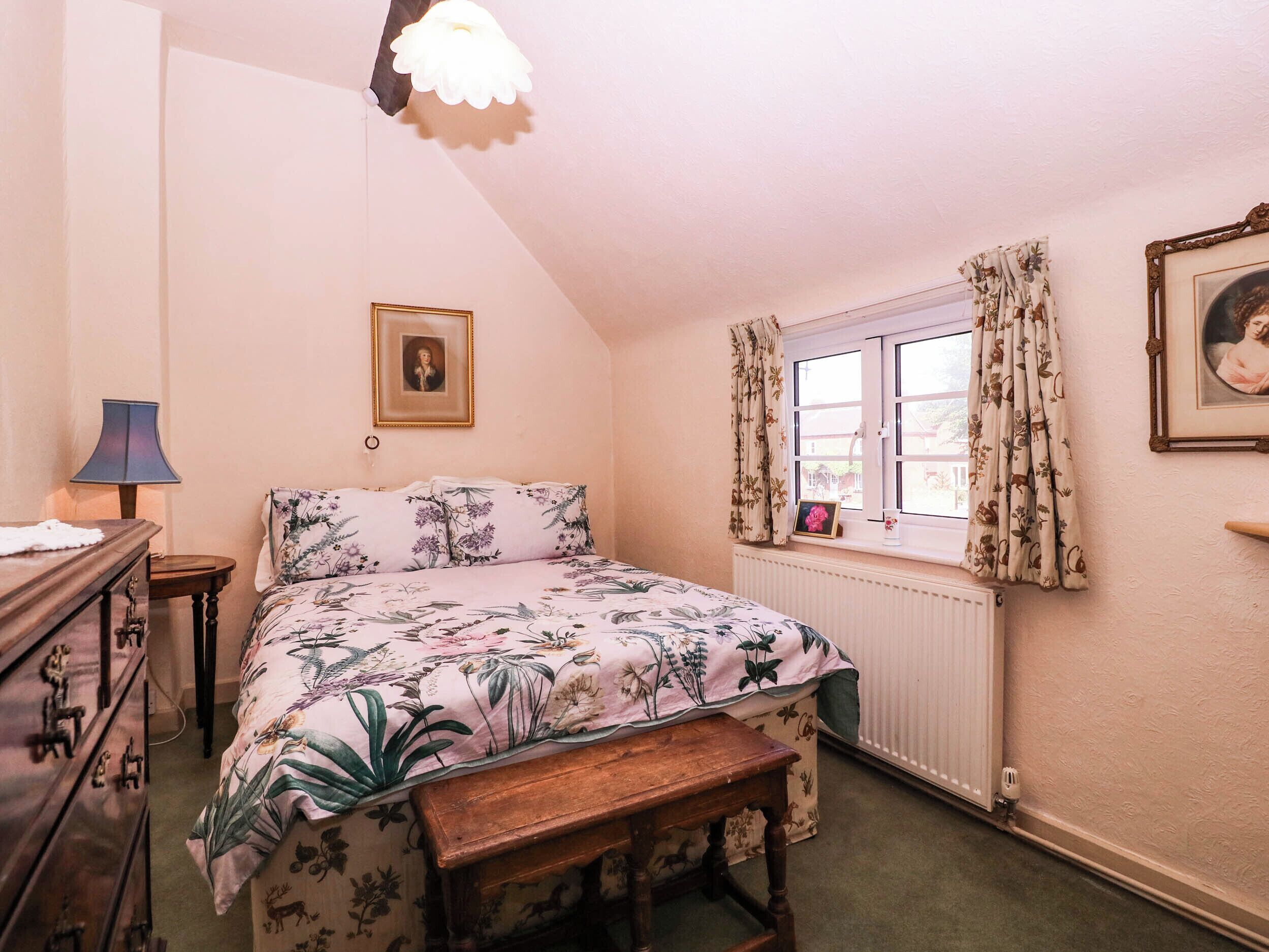 A bedroom with a bed, a dresser, a window with curtains, a picture on the wall, and a lamp.