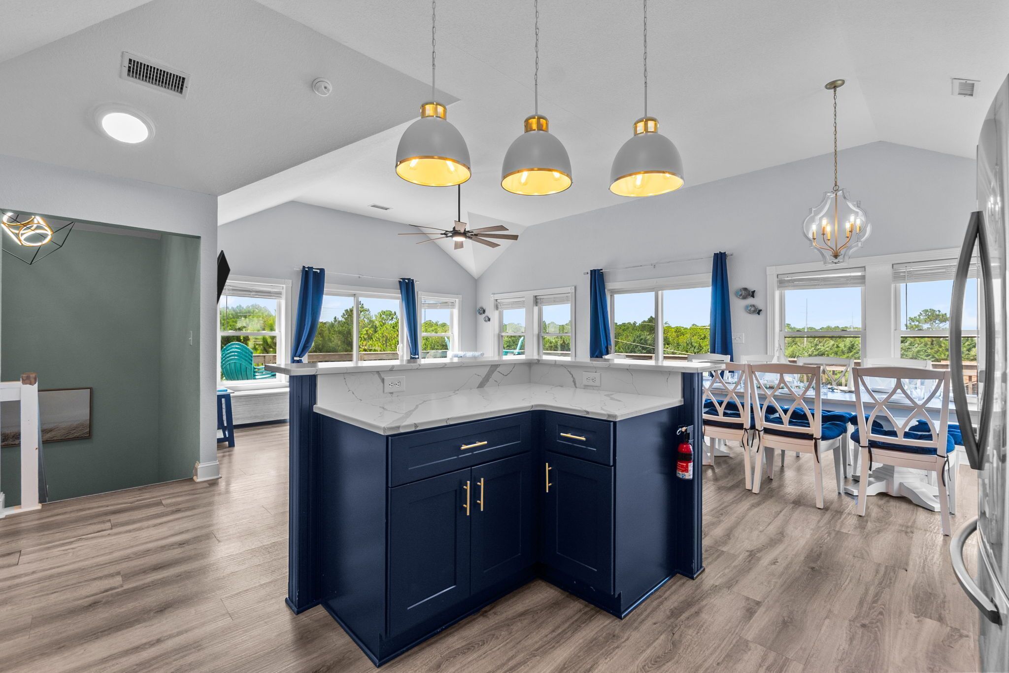 A modern kitchen with dark blue cabinets, a large island, and pendant lighting.