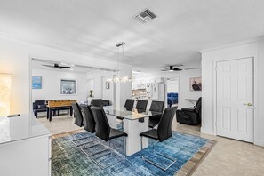 A modern dining area with a glass table, black chairs, and a blue rug. - Beautiful house with Pool & Game Room near Beaches in delightful Bonita Springs (Bonita Springs)
