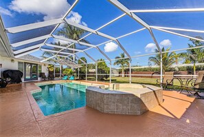 A covered outdoor swimming pool with a stone surround, a barbecue area, and outdoor seating. - Beautiful house with Pool & Game Room near Beaches in delightful Bonita Springs (Bonita Springs)